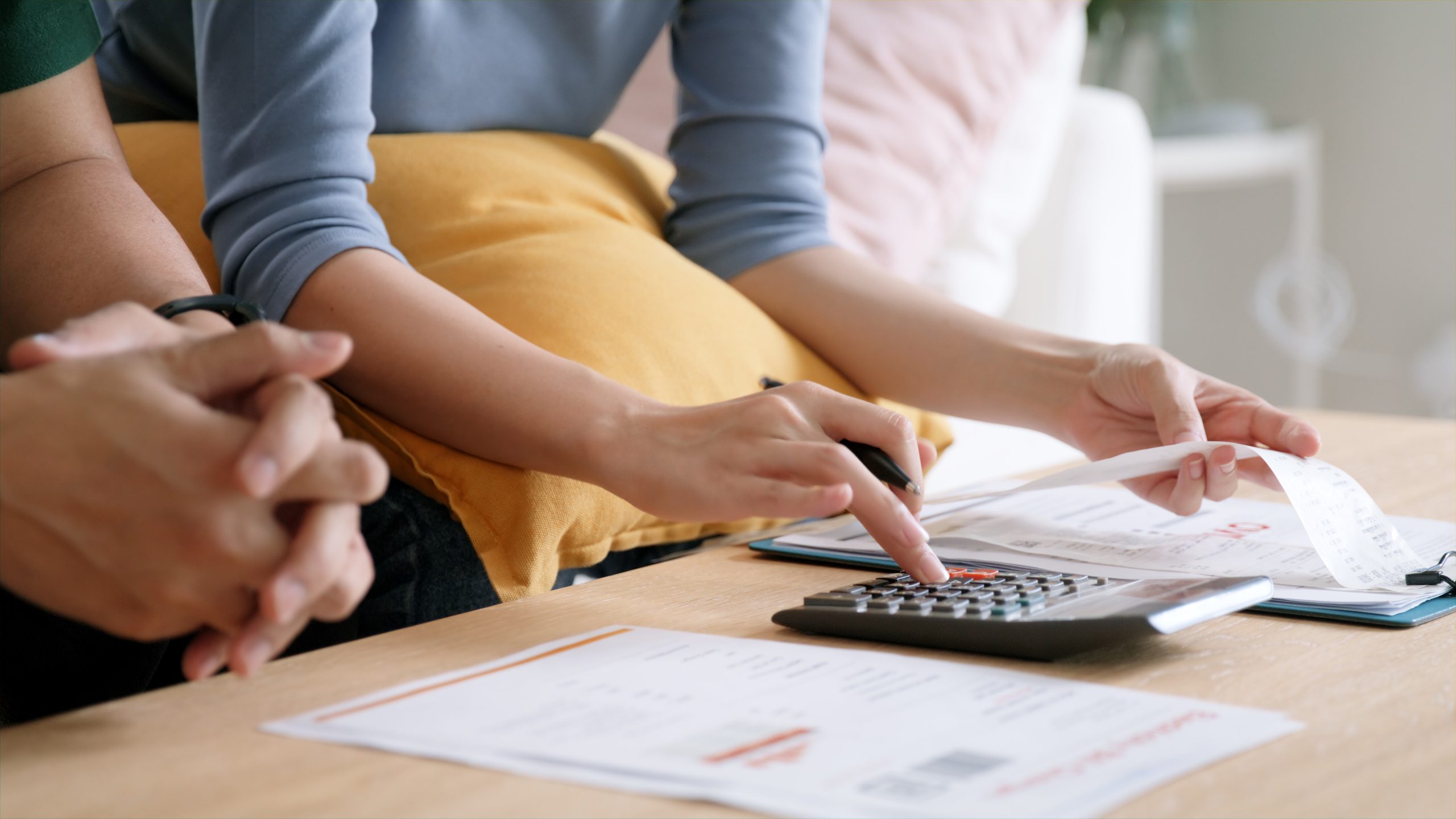 Couple looking worried about computing finances, representing challenges Singapore PR application holders face with rising cost of living and tax burdens