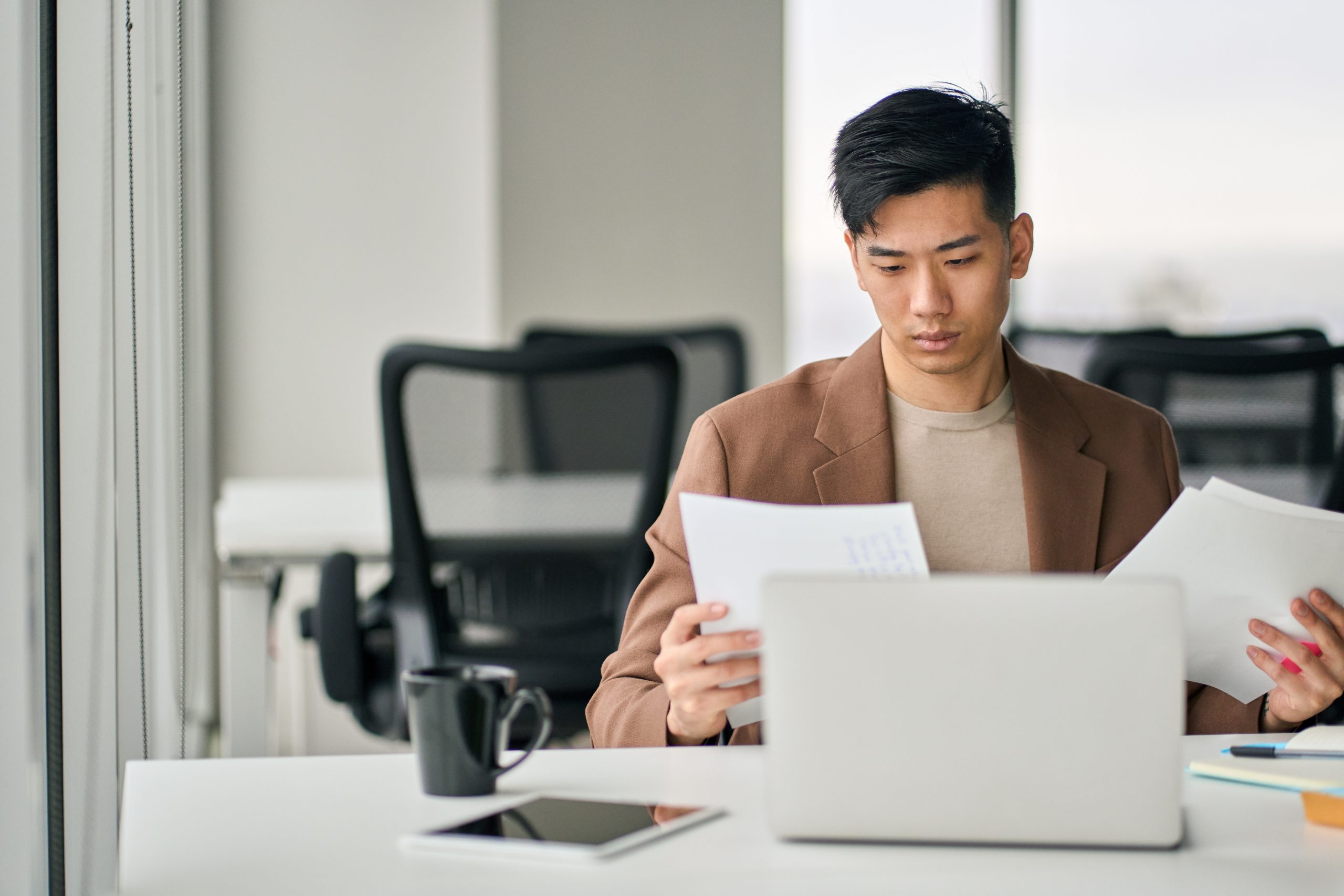 Young Asian professional reviewing documents, relating to Singapore PR application and managing tax relief paperwork